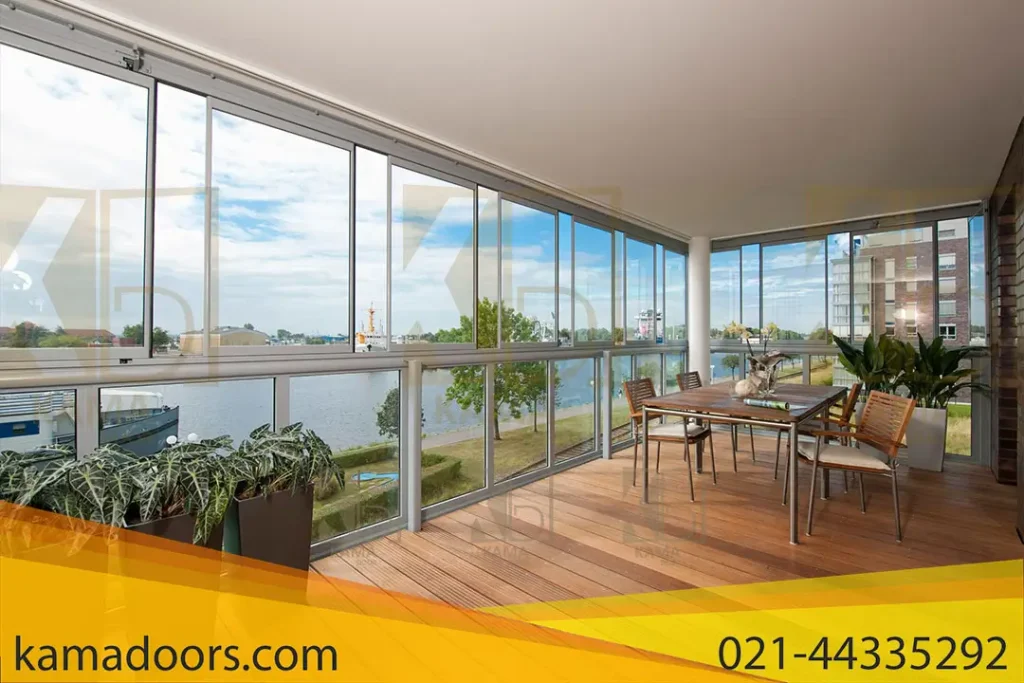 یک بالکن بزرگ با کف چوبی و شیشه بالکنی پنجره ای بزرگ را نشان می‌دهد که نمای وسیعی از بیرون را ارائه می‌ دهد. این شیشه بالکنی پنجره ای توسط شرکت کامادر طراحی و نصب شده است. یک میز ناهار خوری با صندلی وجود دارد و چندین گیاه گلدانی سبزی را به فضا می بخشد. منظره از میان پنجره‌ ها مجموعه‌ ای آرام از آب و ساختمان‌ های دوردست را نشان می‌ دهد و پس‌ زمینه شهری آرام را ایجاد می‌ کند. این محیط آسایش داخل خانه را با منظره بیرونی ترکیب می کند و محیط زندگی آرام را در یک محیط شهری نشان می دهد.