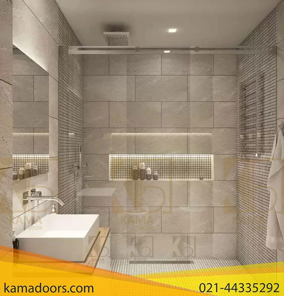 حمام مدرن و شیک را با تمرکز بر ناحیه دوش به تصویر می کشد. حمام دارای محفظه دوش بزرگ با دیوار های شیشه ای تزئین شده با کاشی های خاکستری با بافت های مختلف است. وان سفید در پیش زمینه، در مجاورت دوش قرار گرفته است. قسمت دوش شامل وسایلی مانند سر دوش باران در سقف و سر دوش دستی نصب شده روی دیوار است. یک قفسه فرو رفته در داخل دیوار دوش لوازم آرایش را در خود جای می دهد. کف از کاشی های بافت دار تشکیل شده است که تکمیل کننده کاشی های دیوار است. یک حوله روی میله ای که به یکی از دیوارهای شیشه ای وصل شده است آویزان است.