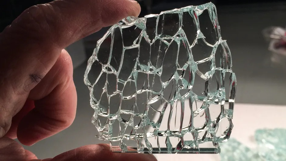 نمای نزدیک از دست فردی را نشان می دهد که تکه ای از شیشه ترک شده را در دست گرفته است. شیشه سکوریت به گونه ای طراحی شده است که در هنگام شکستن به منظور ایمنی به قطعات کوچک و کمتر خطرناک تبدیل شود و این شیشه این الگو را نشان می دهد. شبکه ترک ها و تکه های کوچک و تقریبا مکعبی شیشه از ویژگی های شکستگی شیشه سکوریت شده است. پس زمینه خارج از فوکوس است، اما به نظر می رسد ممکن است تکه های شیشه شکسته بیشتری روی سطح پشت دست وجود داشته باشد.