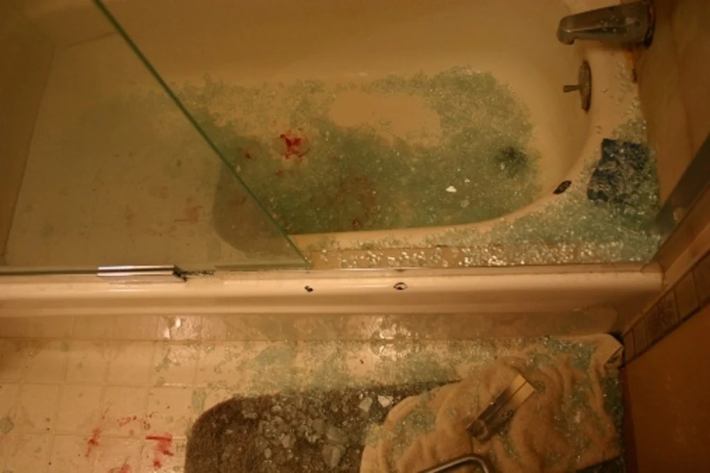 یک صحنه از شیشه حمام را با آسیب قابل توجه نشان می دهد. درب شیشه‌ای دوش شکسته است و تکه‌های شیشه در وان و کف حمام پخش شده است. لکه‌های قرمز رنگی وجود دارد که می‌توان آن را به خون تعبیر کرد که در داخل وان و روی برخی از خرده‌های شیشه قابل مشاهده است. یک حوله، همچنین با برخی علائم قرمز، روی زمین در میان شیشه های شکسته دیده می شود. علت آسیب نیز مشخص نیست، اما نشان دهنده شکستن شدید یا تصادفی درب دوش است. در وان حمام آب وجود دارد که نشان می‌دهد ممکن است وان در زمان حادثه استفاده می‌شده است.