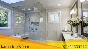 یک فضای داخلی حمام مدرن را نشان می دهد که توسط شیشه حمام لولایی طراحی شده است. رنگ‌ ها روشن و مطبوع هستند، با طرح رنگی که شامل رنگ‌ های سفید، خاکستری و چوب روشن طبیعی است. منطقه دوش توسط شیشه حمام لولایی بزرگ در سمت چپ محاصره شده است، با چیزی که به نظر می رسد یک سر دوش باران است. یک وان حمام سفید از طریق دیوار شیشه ای دوش قابل مشاهده است و حس فضا را تقویت می کند. دو سینک با دو آینه بزرگ فریم دار بالای آن ها وجود دارد که طرف مقابل اتاق را منعکس می کند. روی میز، چیزی شبیه یک دسته گل سفید وجود دارد که جلوه ای تزئینی به آن اضافه می کند. نور طبیعی از پنجره ها که منظره ای به فضای سبز دارند وارد می شود و فضایی آرام به اتاق می بخشد. حوله ها به طور مرتب در اتاق قرار می گیرند، که نمایانگر یک فضای داخلی صحنه دار یا طراحی شده است، مانند آنچه ممکن است در لیست املاک یا نمونه کارهای طراحی مشاهده شود. چیدمان و عناصر طراحی نشان دهنده تمرکز بر طراحی لوکس و معاصر است. کیفیت مواد و پرداخت‌ ها نشان‌ دهنده یک ویژگی با کیفیت بالاتر یا ویترینی است که برای جذب مشتریان فهیم طراحی شده است.