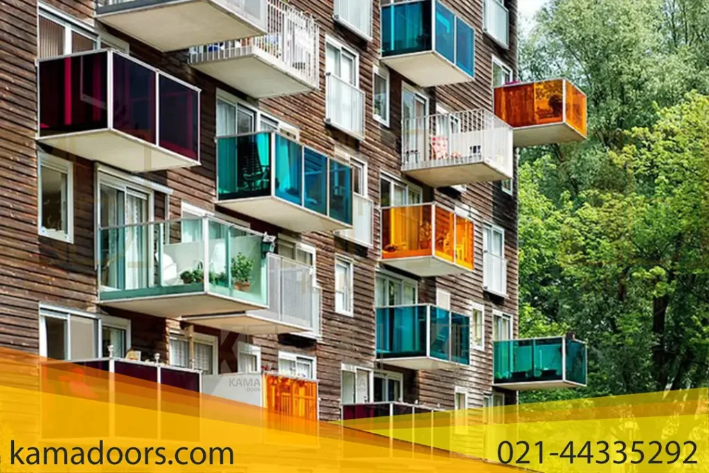 یک ساختمان چند طبقه با طراحی معماری چشمگیر را نشان می دهد. این ساختمان دارای یک سری بالکن است که هر کدام در شیشه محصور شده اند و با رنگ های زنده مانند آبی، سبز، نارنجی و قرمز قاب شده اند. این بالکن های شیشه ای رنگارنگ کامادر با طرحی نامنظم از نمای ساختمان بیرون زده اند و زیبایی مدرن و چشم نوازی را ایجاد می کنند. این ساختمان توسط درختان سبز احاطه شده است که تضاد طبیعی را به ساختار ساخته دست بشر اضافه می کند.